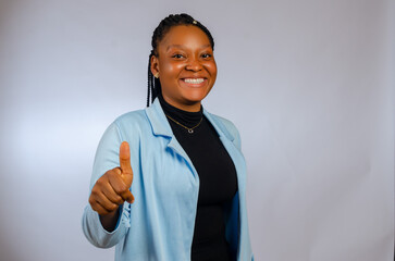 beautiful african lady smiling showing approval with her thumbs up, isolated white background