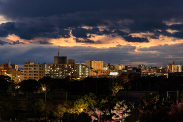 Obraz premium Dramatic clouds after sunset over low rise buildings by park