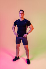 Fototapeta na wymiar Athletic man with fit muscular body training in studio - Active man doing a workout, colorful lighting and background, concepts about fitness, sport and healthy lifestyle