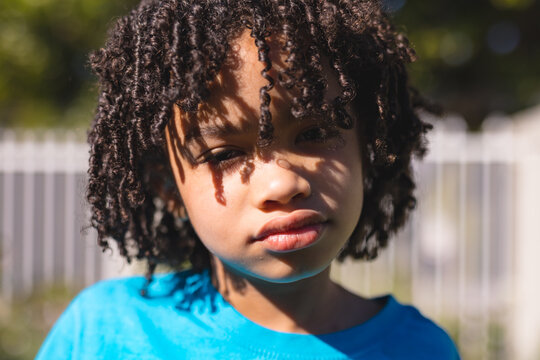 Close-up portrait of cute hispanic boy with black curly hair at backyard on sunny day