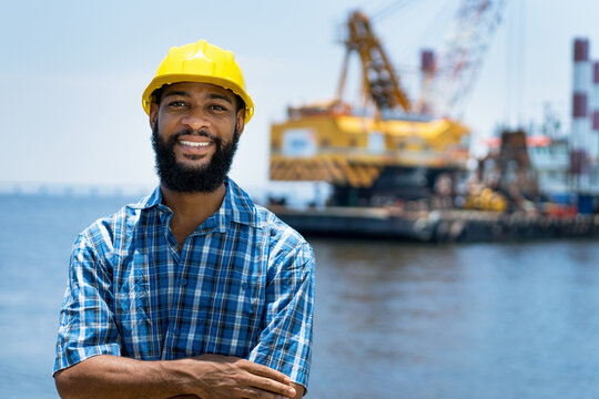Portrait of laughing africa american offshore worker with digger and ocean
