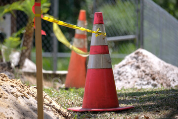 Yellow warning cones and tape as protective restriction barrier at industrial construction site....