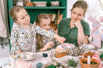 easter holiday time in spring season. happy family candid little kids sisters girls together mother have fun at home decorating table for lunch or dinner. traditional food. festive home decor