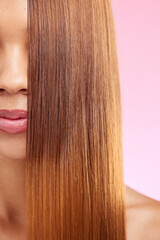 Beauty, hair and half face of black woman isolated in studio with pink background for salon advertising. Haircare, straightener and Brazilian hairstyle on model for luxury growth product promotion.