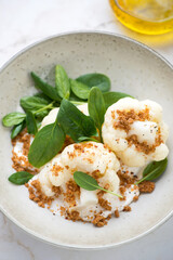 Close-up of steamed cauliflower with spinach, ricotta and breadcrumbs in a beige plate, vertical shot