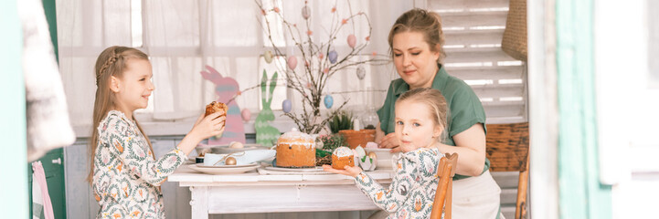 Obraz na płótnie Canvas easter holiday time in spring season. happy family candid little kids sisters girls together mother have fun at home decorating table for lunch or dinner. traditional food. festive home decor. banner