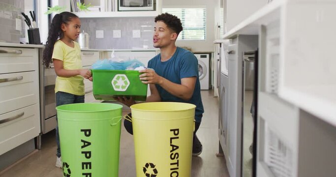 Happy biracial father and daughter sorting waste together