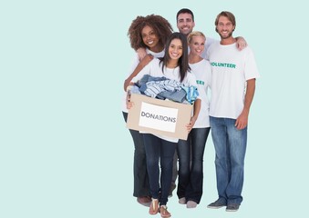 Group of diverse volunteers holding donation boxes smiling against copy space on green background