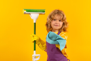 Child doing housework. Children helping with housekeeping, cleaning the house. Housekeeping at home. Cute child boy helping with housekeeping on yellow studio backdround.