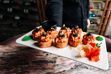 Man chef hand holding a plate full of sushi