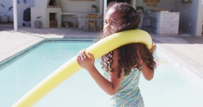 Portrait of happy biracial girl looking at camera at swimming pool