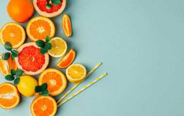 top view of orange grapefour and lemon citrus fruits with  herbs on blue background