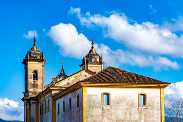 Fototapeta na wymiar Towers of an old historic baroque church seen from behind in the city of Ouro Preto during dusk with the mountains in the background