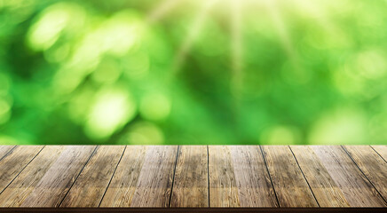 Wooden table top with natural green blurred background or various leaves, fresh bright sunlight, product empty concept.