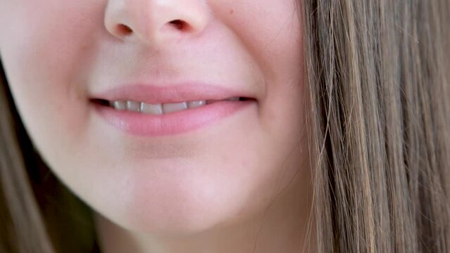 beautiful young girl licks lips close-up and smiles clean straight teeth very tasty food appetite desire to eat sexuality lust pleasure dry lips taste of food bite lip close-up one lower part of face