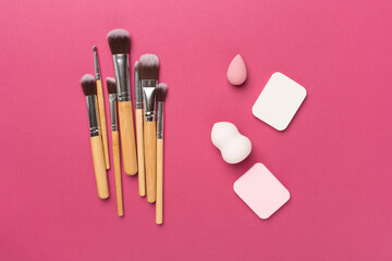 Make up brushes and sponges on color background, top view