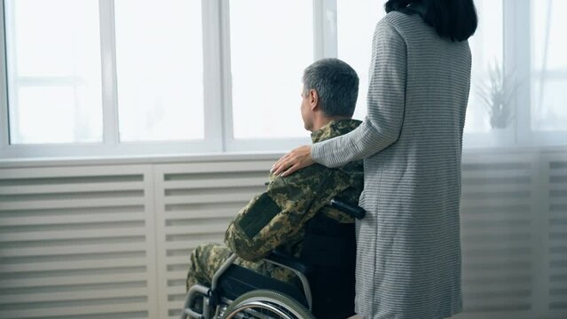 Back view of wife supporting her soldier husband with disability, family