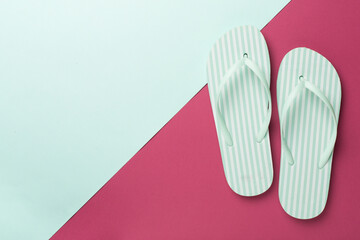 Striped flip flops on color background, top view