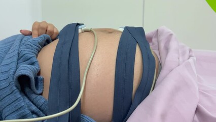 Asian pregnant woman with prenatal ultrasound scan woman wearing fetal monitoring belt