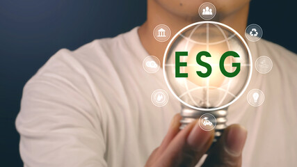 Hand holding light bulb with ESG icon. environmental conservation and modernization of technology...