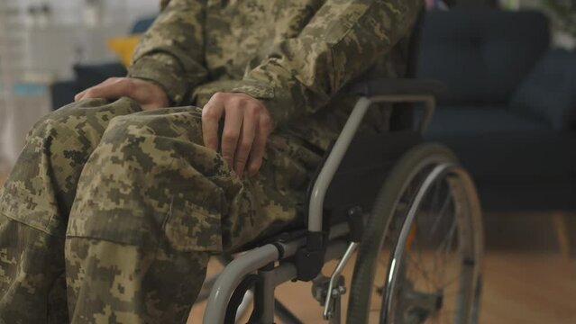 Closeup of male veteran wheelchair user feeling leg cramps, medical condition