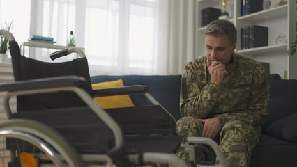 Military veteran with disability feeling depressed, looking sadly at wheelchair