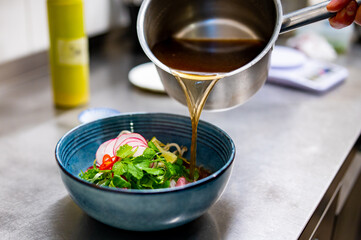 Close up of chef's hands cooking asian pho bo soup on restaurant kitchen