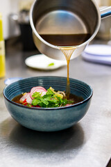 Close up of chef's hands cooking asian pho bo soup on restaurant kitchen