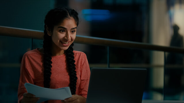 Happy amazed arabian woman businesswoman winner read paper documents talk by video conference achieve good test results get successful online job interview win bid auction business deal financial goal