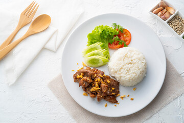 Stir-Fried Pork with Garlic and pepper with cooked thai jasmine rice in white plate,popular Thai Street food.Top view