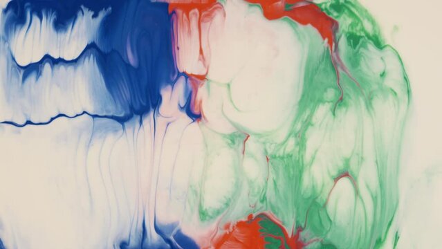 Blue, green and red colors mixing in white paint fluid art background. Dynamic liquid blending. Multicolor flow with swirls and waves creative texture