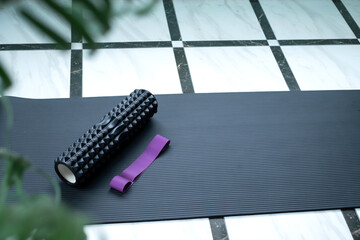 roller for massage and fitness band lie on a black yoga mat