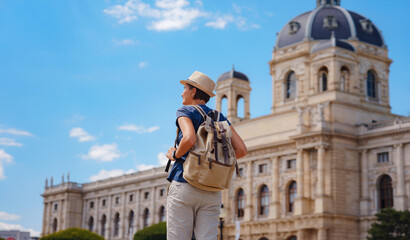 Obraz premium summer female solo trip to Europe, happy young woman walking on european street. Maria Theresa square near museum of Natural history in Vienna.