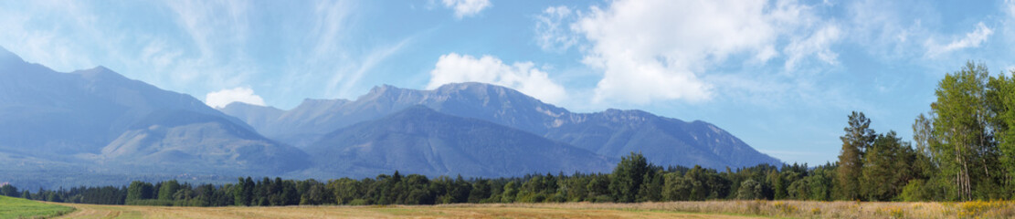 slovakia countryside in summertime. high tatra ridge in the distance. clouds on the blue sky