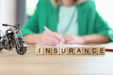 Insurance word on wooden blocks in row and small model of motorbike