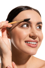 close up of happy young woman styling eyebrows with brush and gel isolated on white.