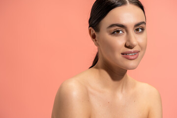 portrait of smiling young woman with bare shoulders and flawless makeup isolated on pink.