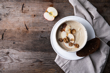 Bowl of homemade Jerusalem artichoke and apple cream soup on wooden table.