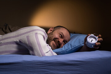 Alarm clock for a man who lies on the bed and smiles. Ease of waking up, good sleep, the right mode...