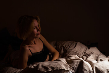 A woman in bed in the dark does not sleep. Insomnia, sleep disturbance, circadian rhythm concept.
