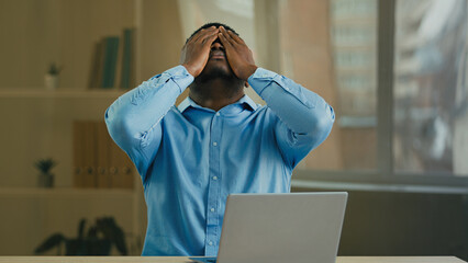 Desperate sad angry African American businessman manager entrepreneur working with laptop at office...