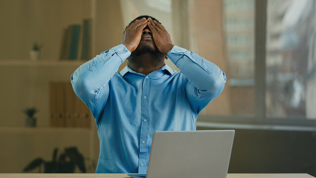 Desperate sad angry African American businessman manager entrepreneur working with laptop at office has computer problem broken device send wrong email message bad news or crash mistake error failure