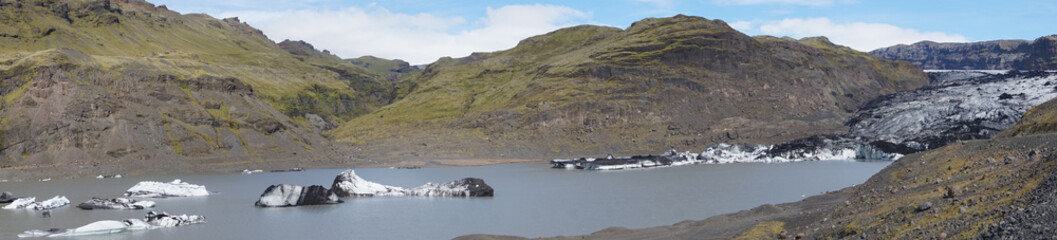 Glacier and ice chunks floating in lake, panorama - Solheimajokull, Iceland