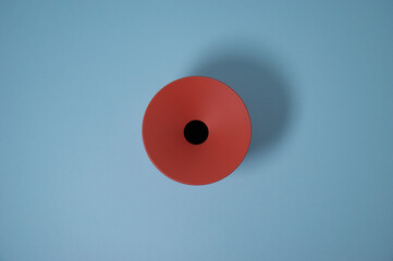 round orange/brick colored container seen from above, with concave hole in the center on a light blue background