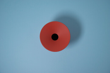 round orange/brick colored container seen from above, with concave hole in the center on a light...