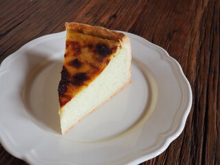 Slice of french custard tart (flan pâtissier) on a white plate, rustic wooden background