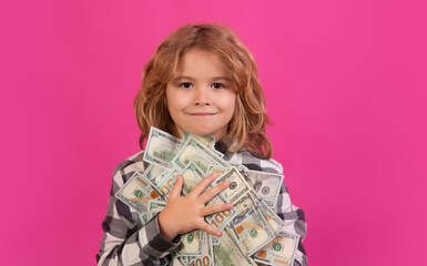 Money win, big luck. Child showing money dollar bills, standing dreamy of rich against isolated pink red studio background.