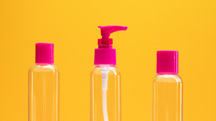 Closeup fuchsia travel bottle kit for liquids, cream. Toiletries Beauty Kit on yellow orange background. Airplane approved luggage reusable container size. Summer time, vacation concept Horizontal.