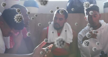 Animation of virus cells floating over diverse group of male football players in changing room - Powered by Adobe