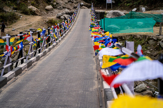 Sacred religious multicolored prayer flags placed on both sides of bridge moving in the wind showing a bhuddist prayer incantation common in hill stations in Himachal Pradesh